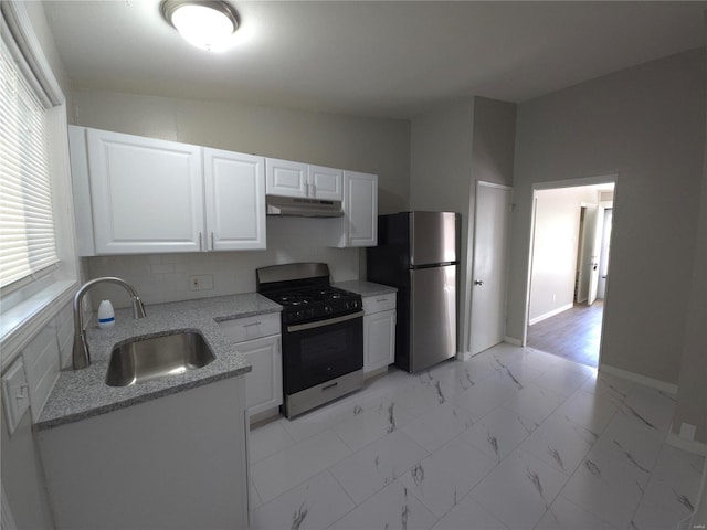 kitchen with sink, light stone counters, white cabinets, stainless steel appliances, and backsplash