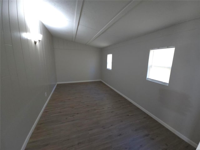 spare room featuring dark wood-type flooring and vaulted ceiling