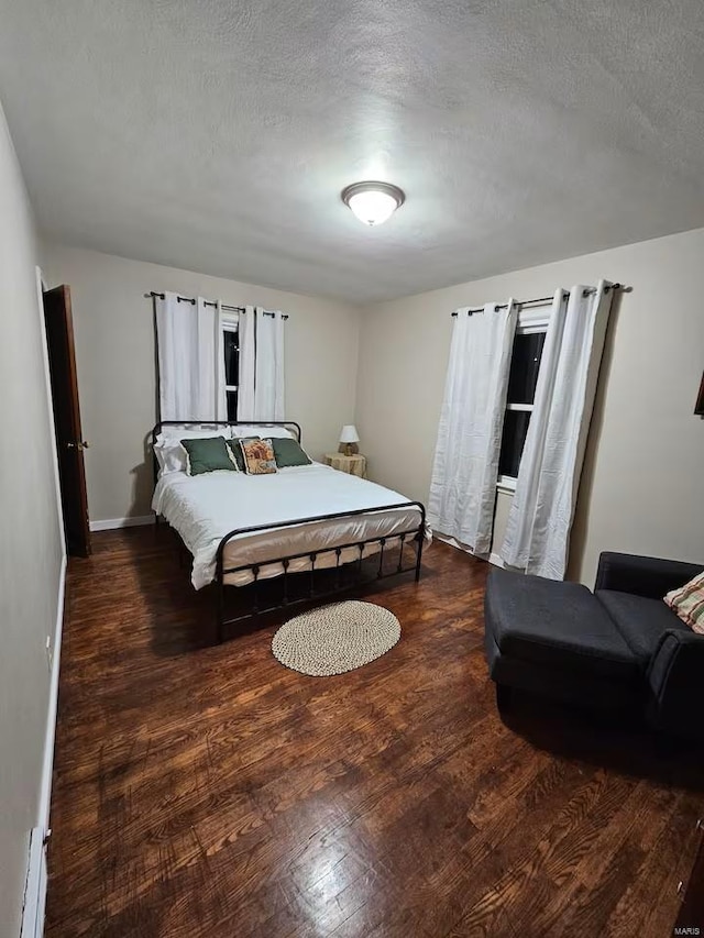 bedroom with a textured ceiling and dark wood-type flooring