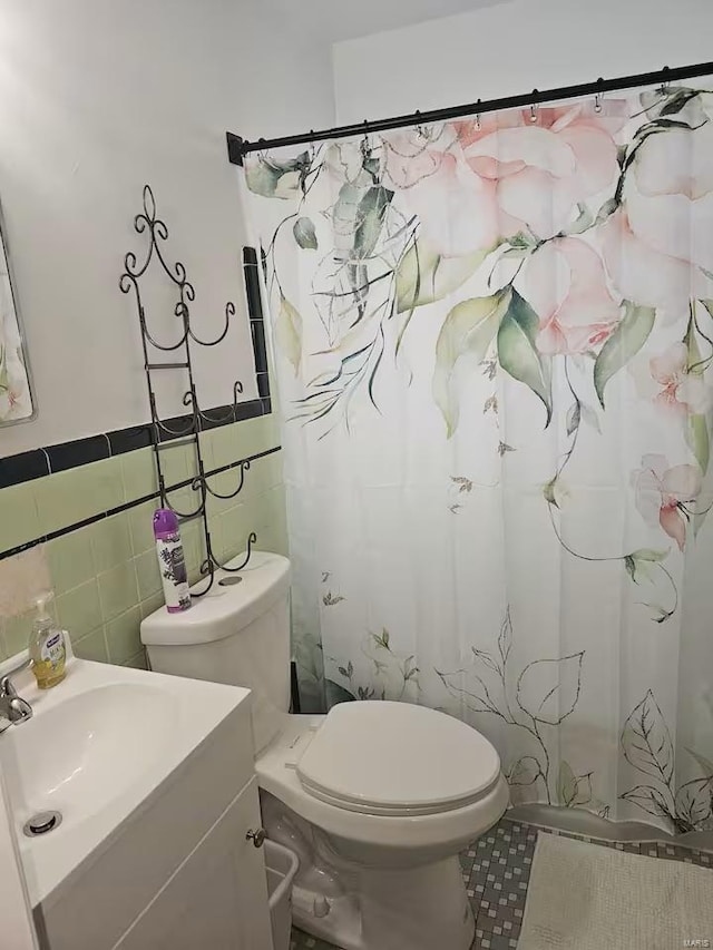 bathroom with vanity, toilet, and tile walls