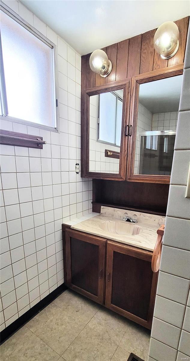 bathroom featuring vanity and tile walls