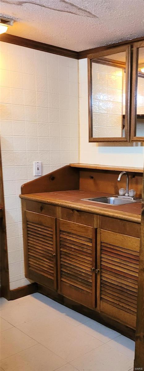 bar featuring a textured ceiling and sink