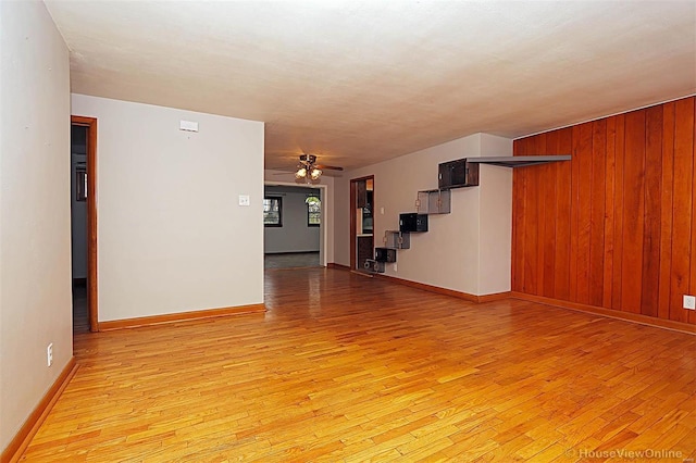 spare room featuring light hardwood / wood-style flooring, ceiling fan, and wooden walls