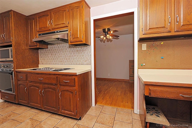 kitchen featuring backsplash, ceiling fan, light wood-type flooring, and appliances with stainless steel finishes