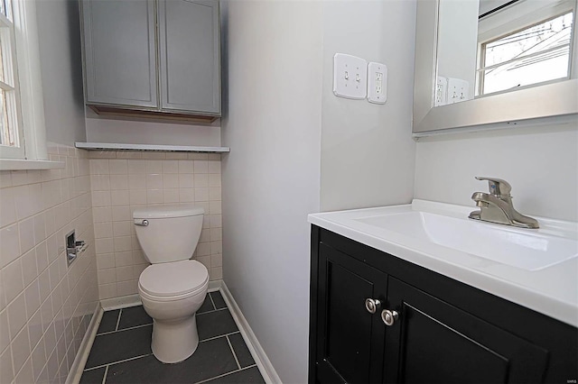 bathroom featuring toilet, vanity, tile patterned floors, and tile walls