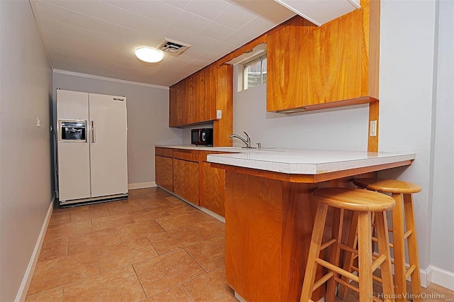 kitchen with a breakfast bar, sink, white fridge with ice dispenser, and kitchen peninsula