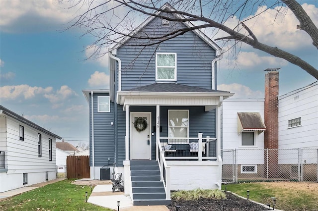 view of front of property featuring cooling unit, covered porch, and a front yard