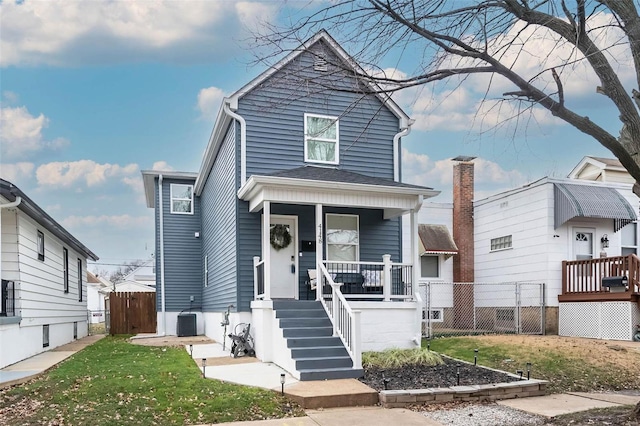 view of front facade with central AC unit, covered porch, and a front yard