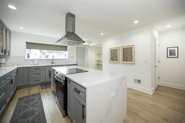 kitchen with light stone counters, light hardwood / wood-style flooring, extractor fan, electric stove, and a kitchen island