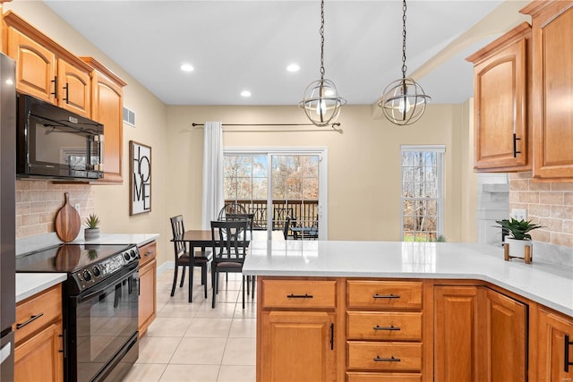 kitchen with tasteful backsplash, kitchen peninsula, pendant lighting, light tile patterned floors, and black appliances