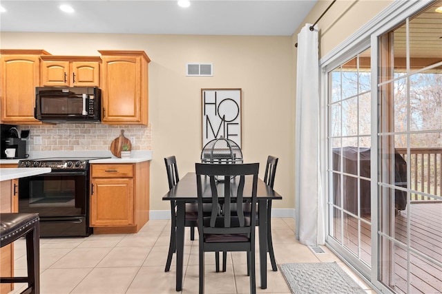 kitchen featuring black appliances, light tile patterned floors, and backsplash