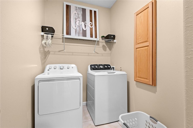 laundry area with cabinets, light tile patterned floors, and washing machine and clothes dryer