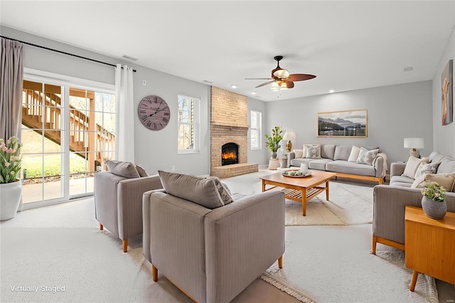 living room with ceiling fan, light colored carpet, and a fireplace