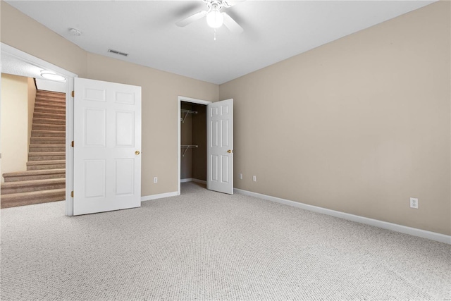 unfurnished bedroom featuring carpet flooring, ceiling fan, a spacious closet, and a closet