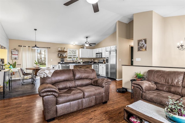 living room featuring ceiling fan with notable chandelier, dark hardwood / wood-style floors, vaulted ceiling, and sink