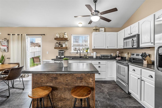 kitchen featuring stainless steel range with electric stovetop, a center island, white cabinetry, and sink