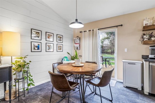 dining area featuring lofted ceiling and wooden walls