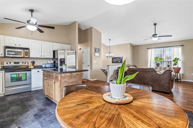 kitchen with stainless steel appliances, decorative light fixtures, white cabinets, a center island, and lofted ceiling