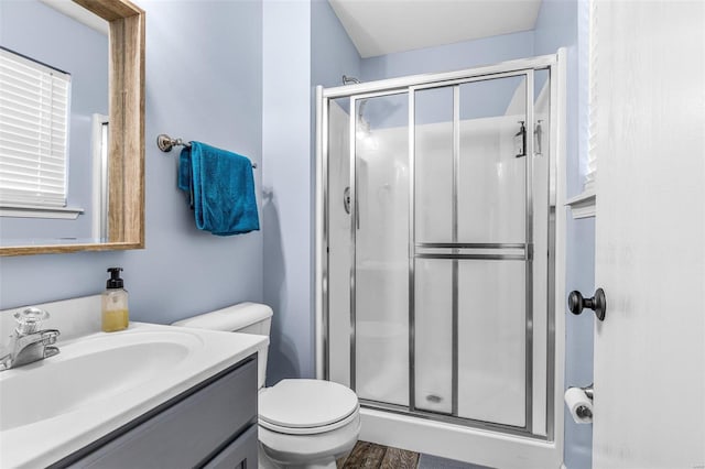 bathroom featuring hardwood / wood-style floors, vanity, toilet, and a shower with door