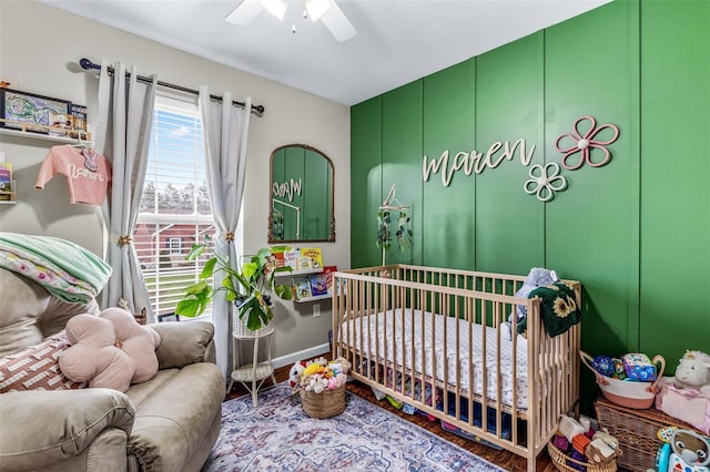 bedroom with ceiling fan, hardwood / wood-style floors, and a crib