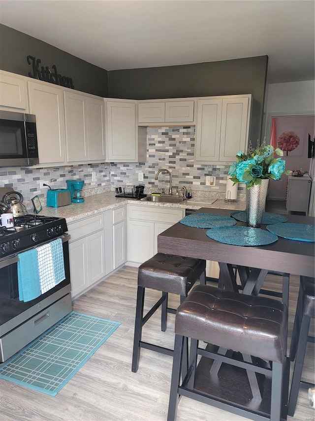 kitchen featuring decorative backsplash, sink, white cabinets, and stainless steel appliances