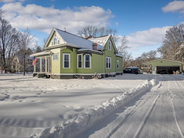 snow covered property featuring a chimney and an outdoor structure