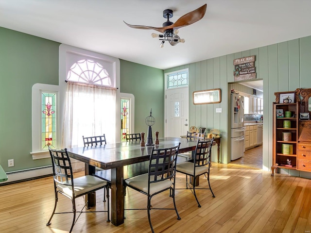 dining space featuring light wood-style floors, baseboard heating, and a ceiling fan