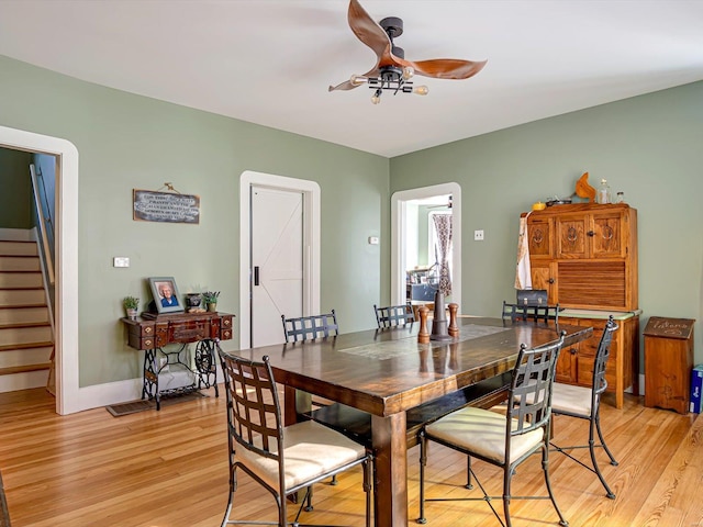 dining room with light wood-style floors, baseboards, stairway, and a ceiling fan