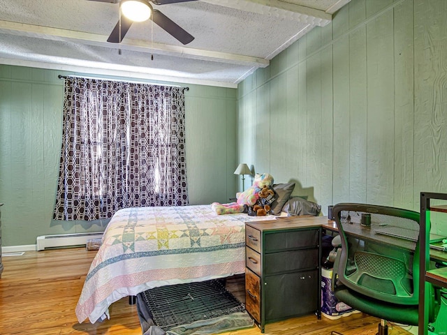 bedroom with a textured ceiling, beamed ceiling, a baseboard radiator, and wood finished floors