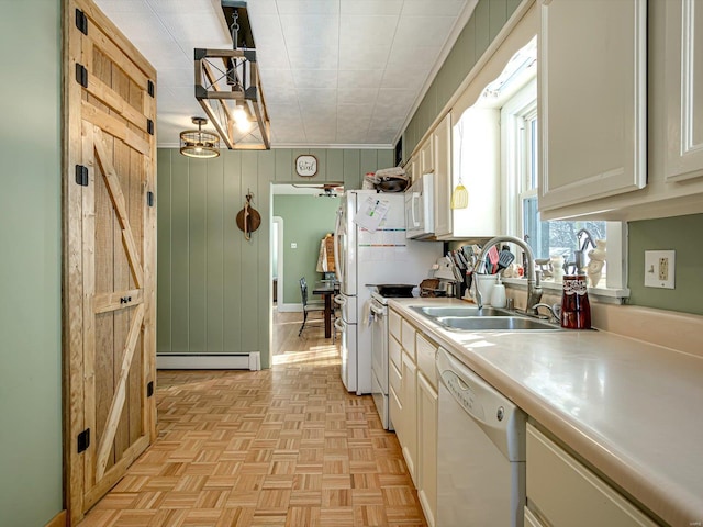 kitchen with white appliances, a barn door, hanging light fixtures, light countertops, and a sink