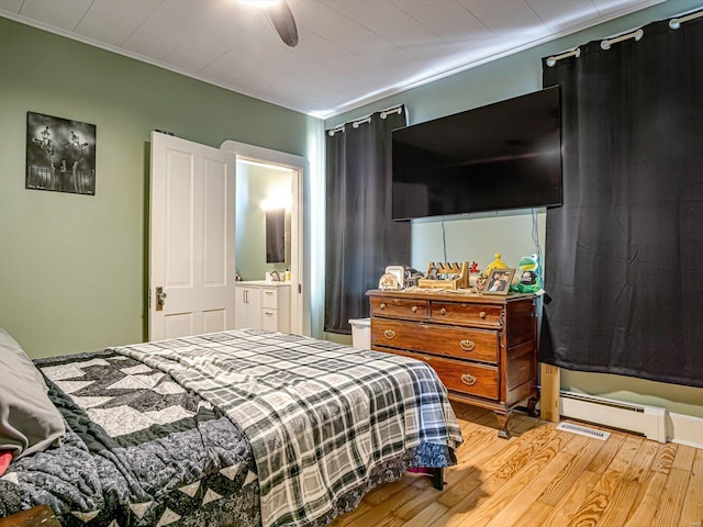 bedroom with a baseboard heating unit, ceiling fan, wood finished floors, and crown molding