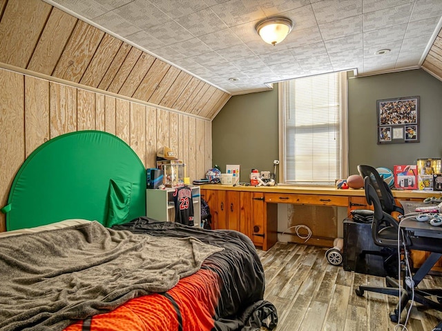 bedroom with lofted ceiling, wood walls, and light wood finished floors