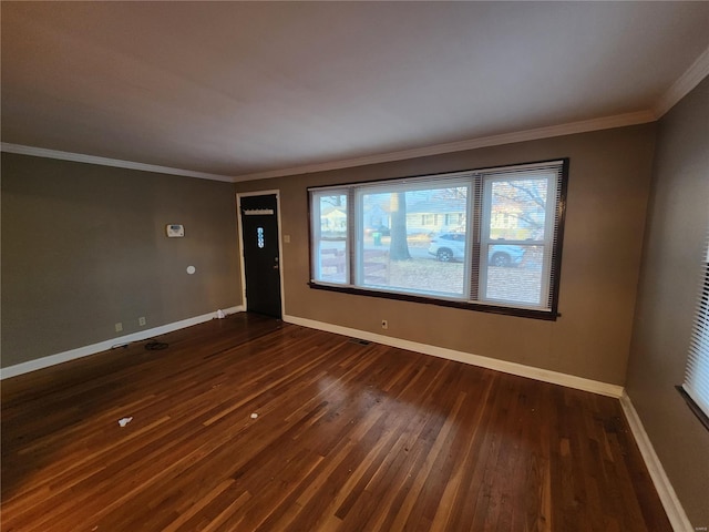 empty room featuring dark wood-type flooring and ornamental molding