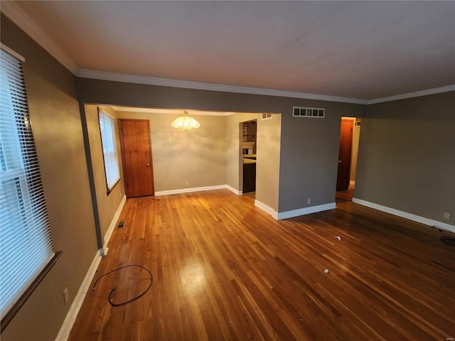 unfurnished living room with hardwood / wood-style flooring, crown molding, and a chandelier