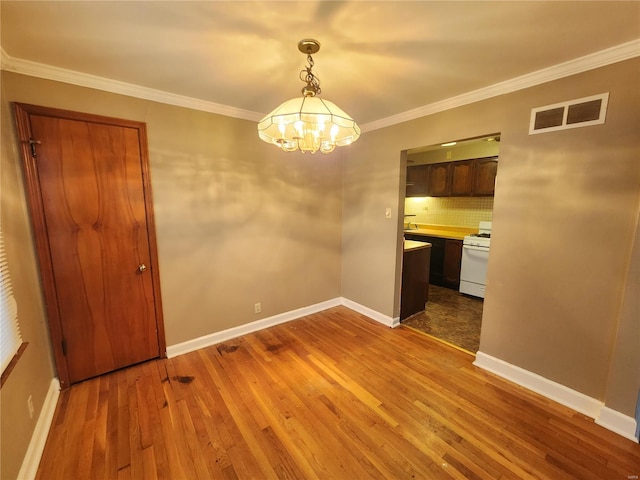 unfurnished dining area featuring crown molding, dark hardwood / wood-style flooring, and a notable chandelier