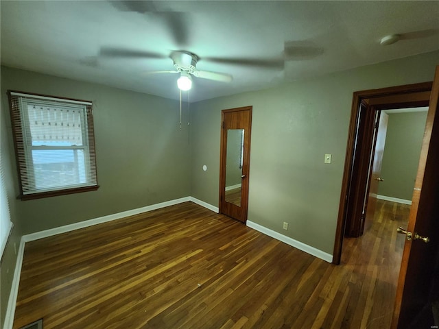 unfurnished bedroom with dark wood-style floors, ceiling fan, visible vents, and baseboards