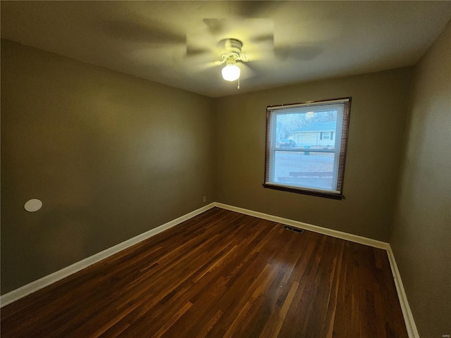 spare room featuring ceiling fan, dark wood-type flooring, visible vents, and baseboards