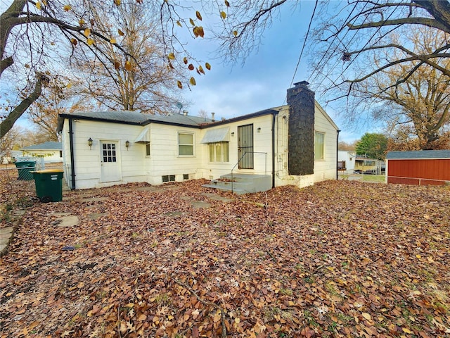 rear view of house with a chimney and fence