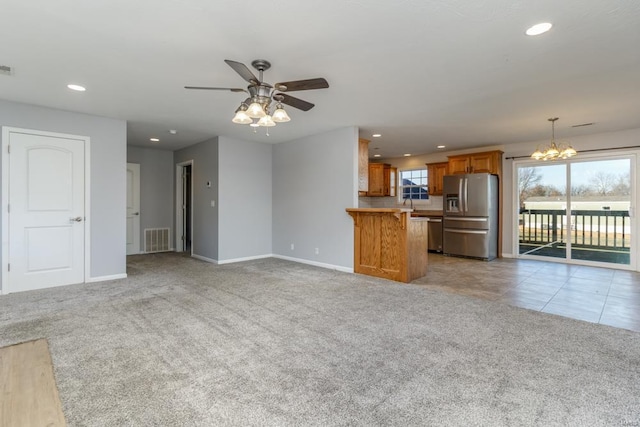 unfurnished living room featuring ceiling fan with notable chandelier and light carpet