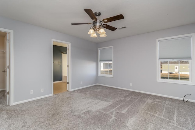 unfurnished bedroom featuring a walk in closet, carpet floors, and ceiling fan