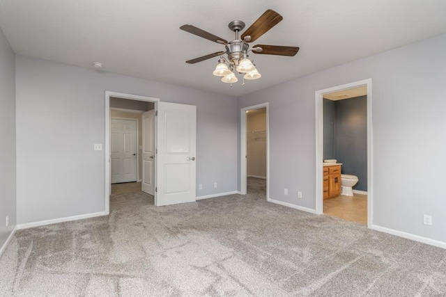 unfurnished bedroom with connected bathroom, ceiling fan, a spacious closet, light carpet, and a closet