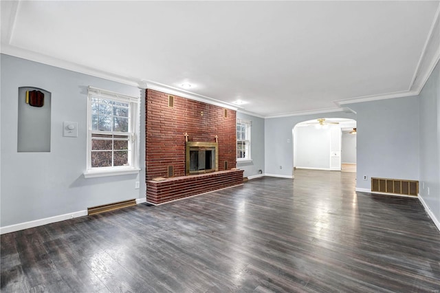 unfurnished living room with dark hardwood / wood-style flooring, ceiling fan, crown molding, and a brick fireplace