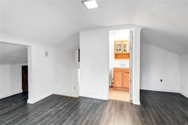 additional living space with dark hardwood / wood-style flooring, vaulted ceiling, and sink