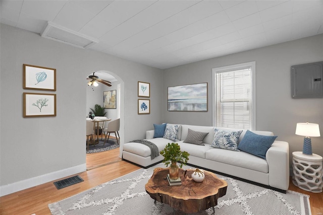 living room with ceiling fan, electric panel, and light hardwood / wood-style flooring