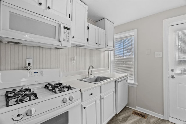 kitchen with wood-type flooring, white appliances, white cabinetry, and sink