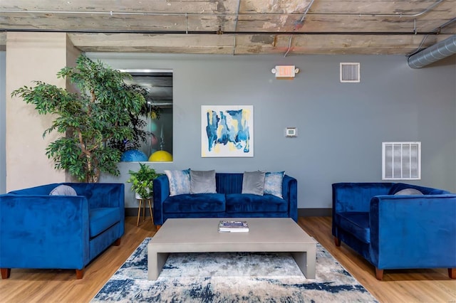 living area featuring visible vents, baseboards, and wood finished floors