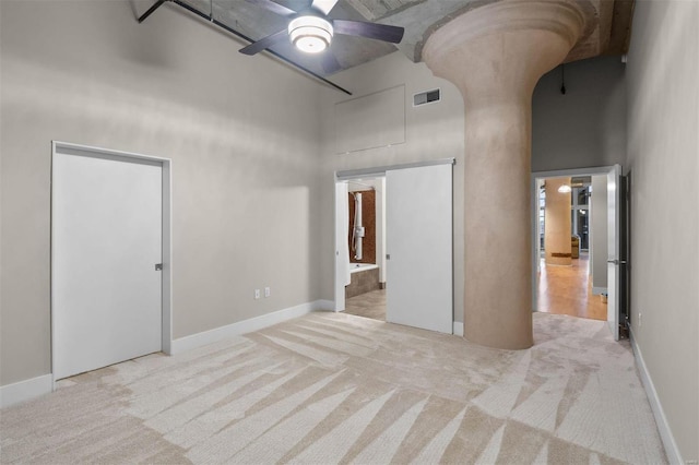 unfurnished room with carpet, a high ceiling, visible vents, and ceiling fan