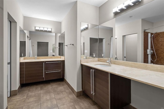 bathroom with baseboards, two vanities, and a sink