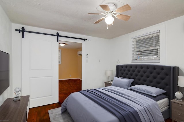 bedroom with dark hardwood / wood-style flooring, a barn door, a textured ceiling, and ceiling fan