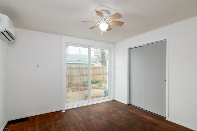 unfurnished bedroom with a wall unit AC, ceiling fan, a closet, and dark hardwood / wood-style floors